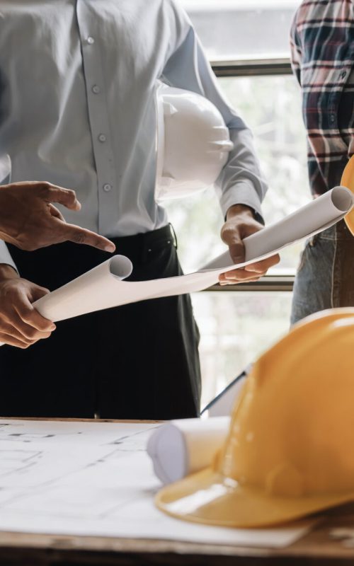 Civil engineer teams meeting working together wear worker helmets hardhat on construction site in modern city. Foreman industry project manager engineer teamwork. Asian industry professional team..